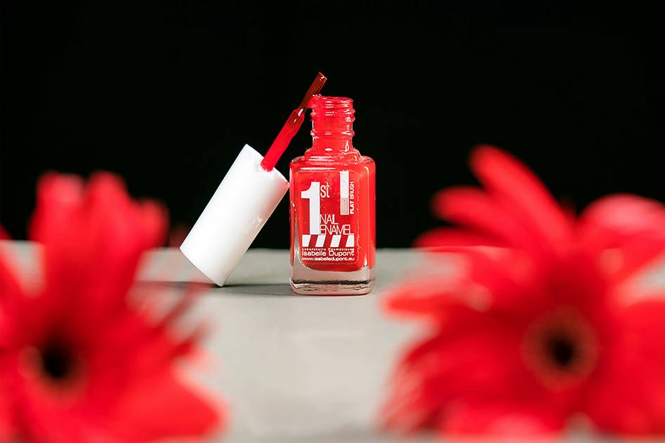 Nail polish remover bottle with cotton pads and manicured hands on marble surface